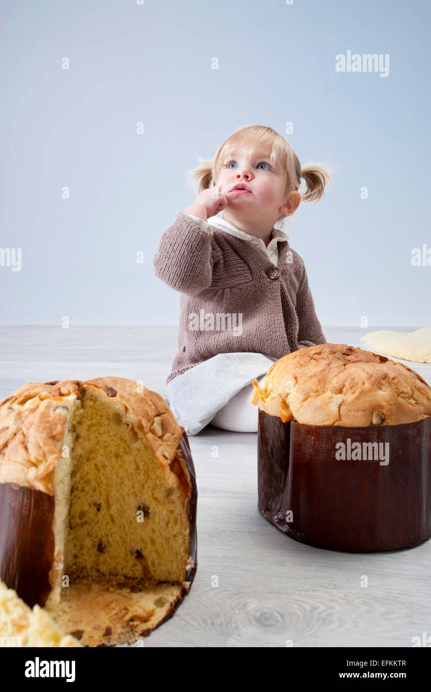 Femmina bambino seduto sul pavimento con pannetone torte Foto Stock