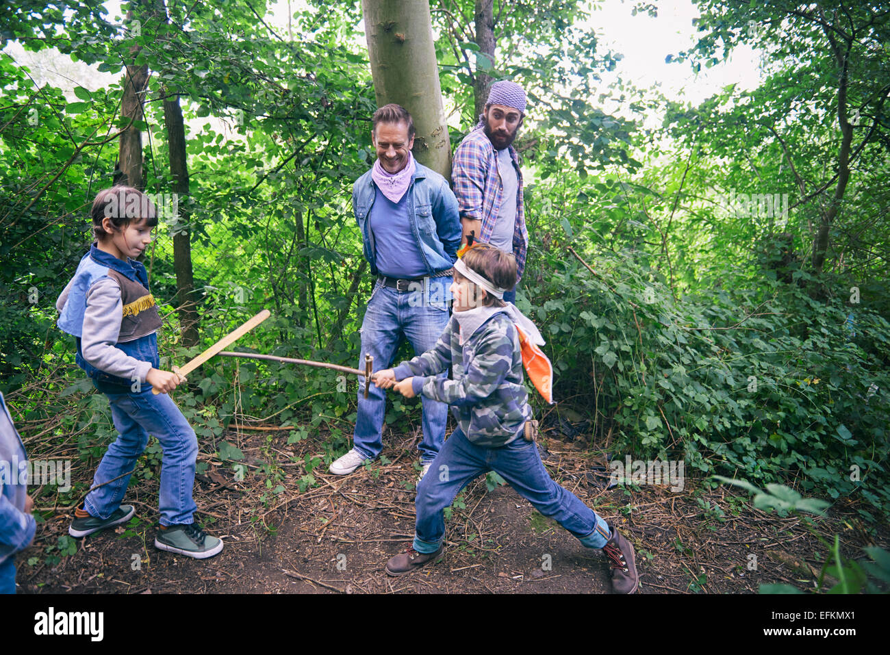Due uomini catturato mentre i ragazzi hanno un duello di spade in foresta Foto Stock
