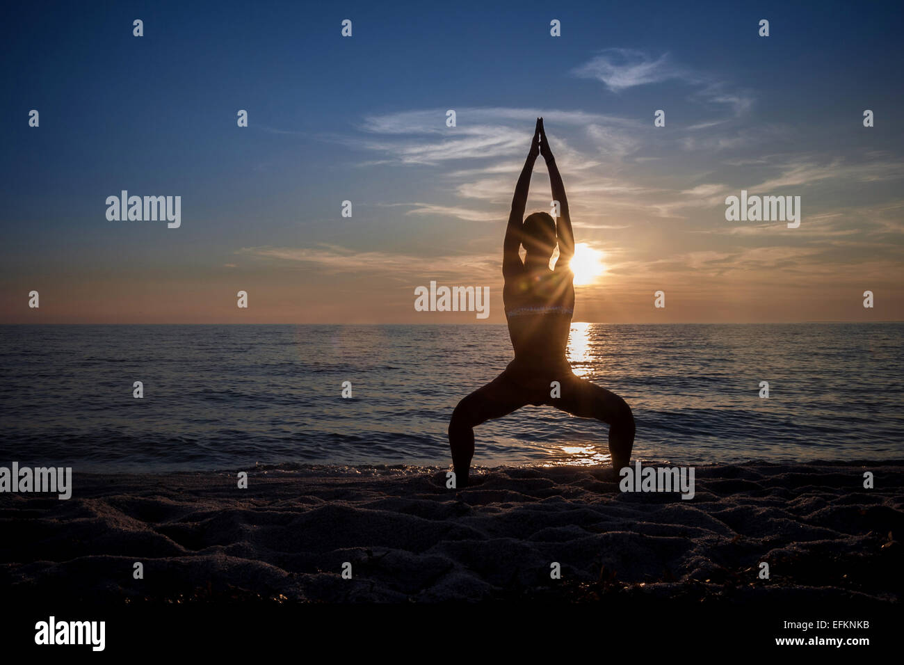 Stagliano giovane donna a praticare yoga sulla spiaggia al tramonto, Oristano, Sardegna, Italia Foto Stock