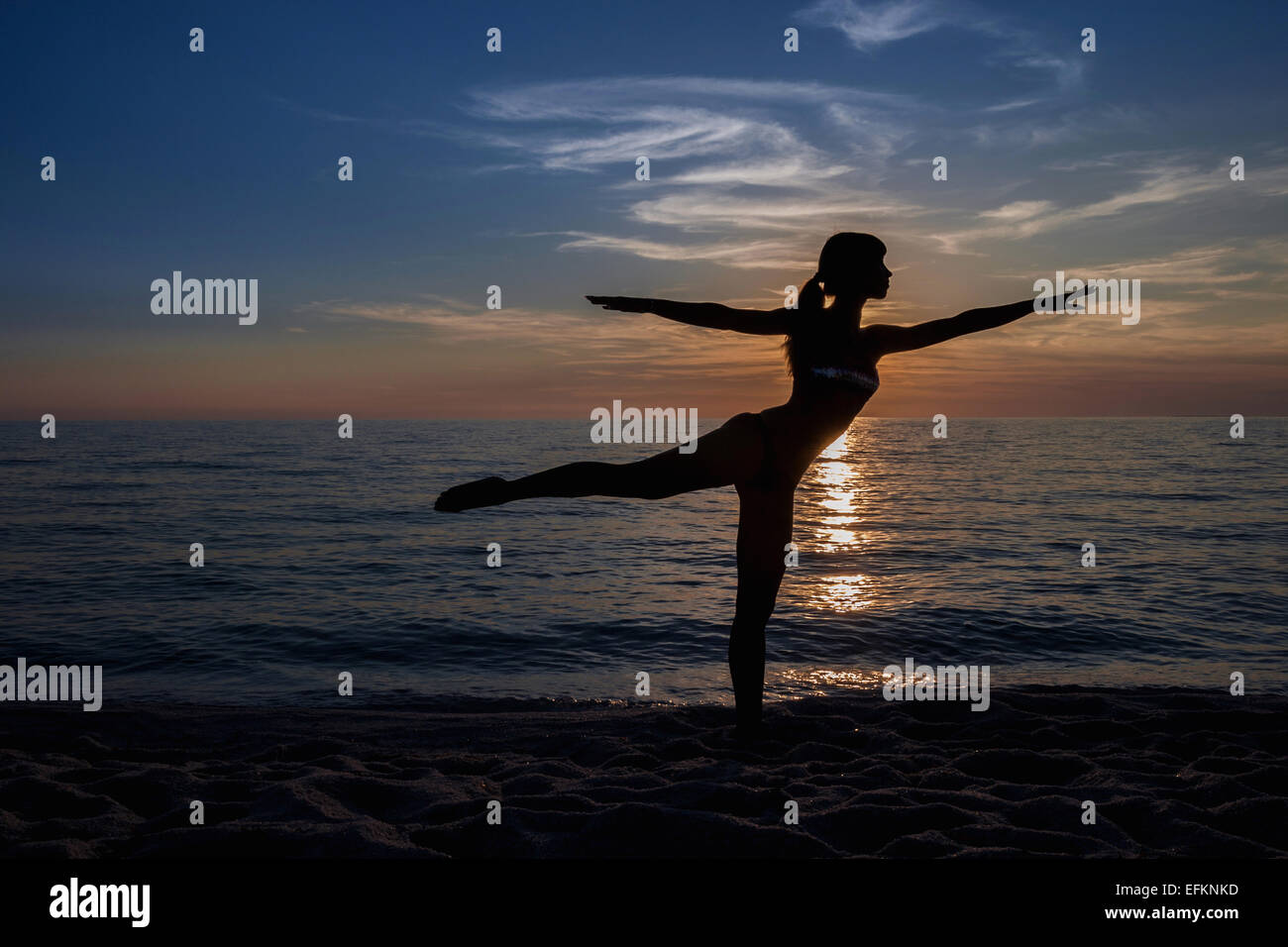 Stagliano giovane donna a praticare yoga pone sulla spiaggia al tramonto, Oristano, Sardegna, Italia Foto Stock