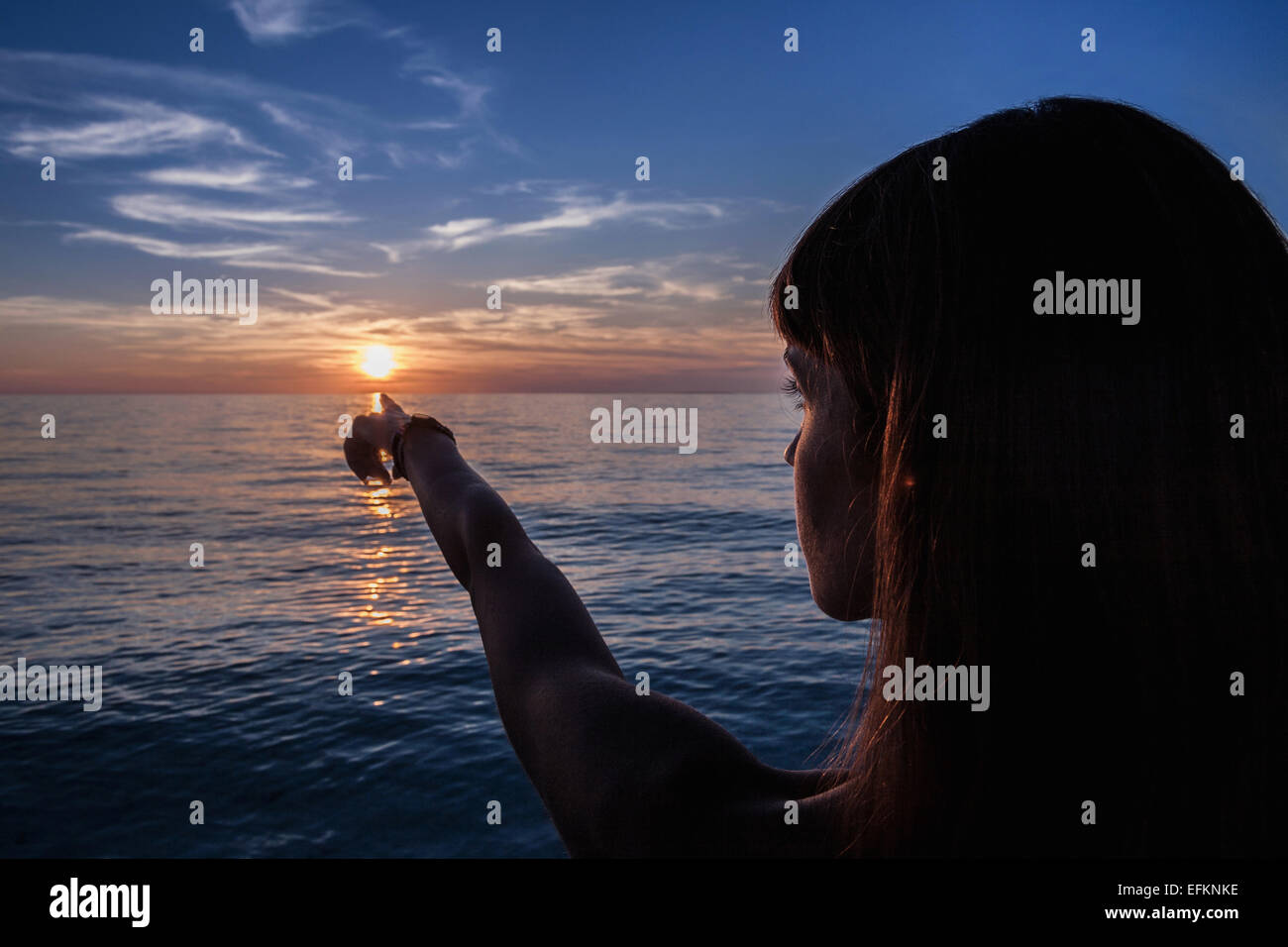 Stagliano giovane donna rivolta al tramonto dalla spiaggia, Oristano, Sardegna, Italia Foto Stock
