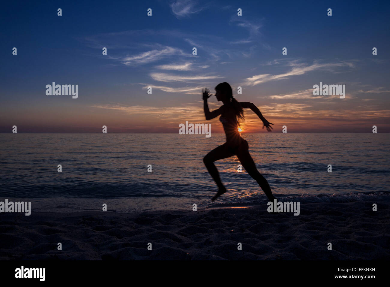 Stagliano giovane donna in esecuzione sulla Sunset beach, Oristano, Sardegna, Italia Foto Stock