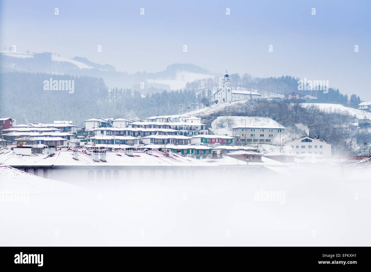 Vista panoramica del villaggio di Azkoitia in inverno con la neve e della Chiesa di San Martino, Paesi Baschi Foto Stock