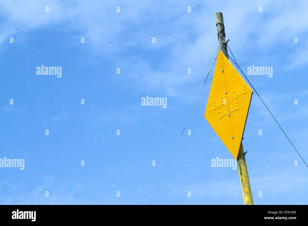 Giallo cavo telefonico segno sul palo del telegrafo contro il cielo blu Foto Stock