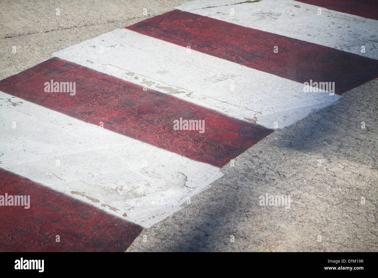 Dettaglio della rossa e bianca a strisce attraversamento pedonale dipinta su strada concreta Foto Stock