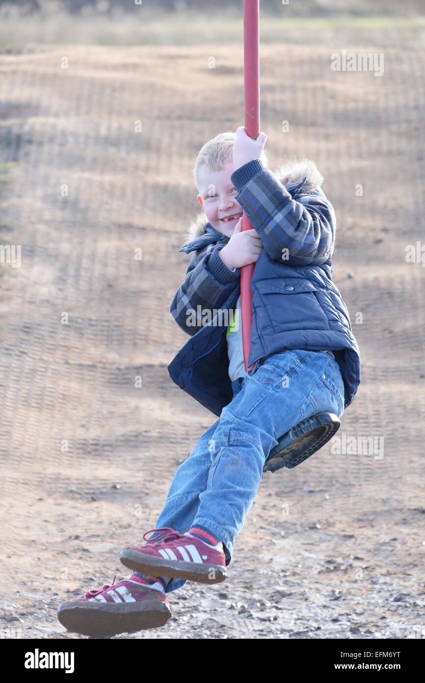 Ragazzo che sorride su zip-filo ride al parco giochi avventura, Brockholes Riserva Naturale, Preston, Lancashire Foto Stock