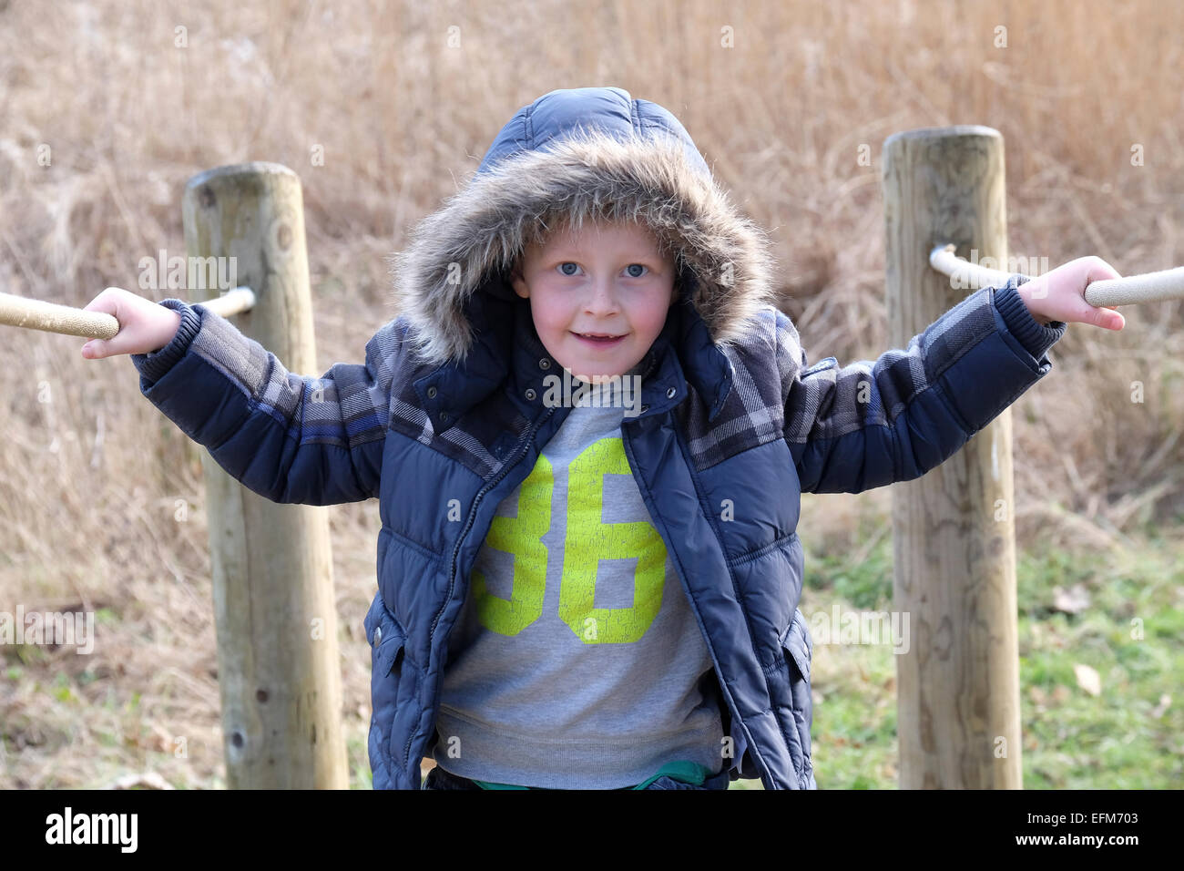 Ragazzo attraversando il ponte sul parco giochi avventura Foto Stock