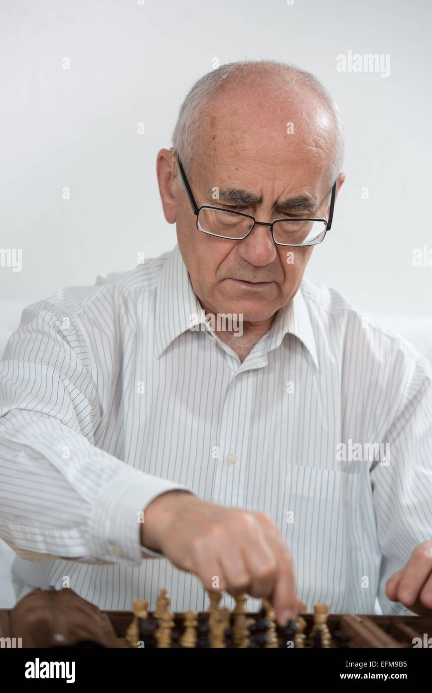 Il vecchio uomo, indossando occhiali, giocare a scacchi Foto Stock