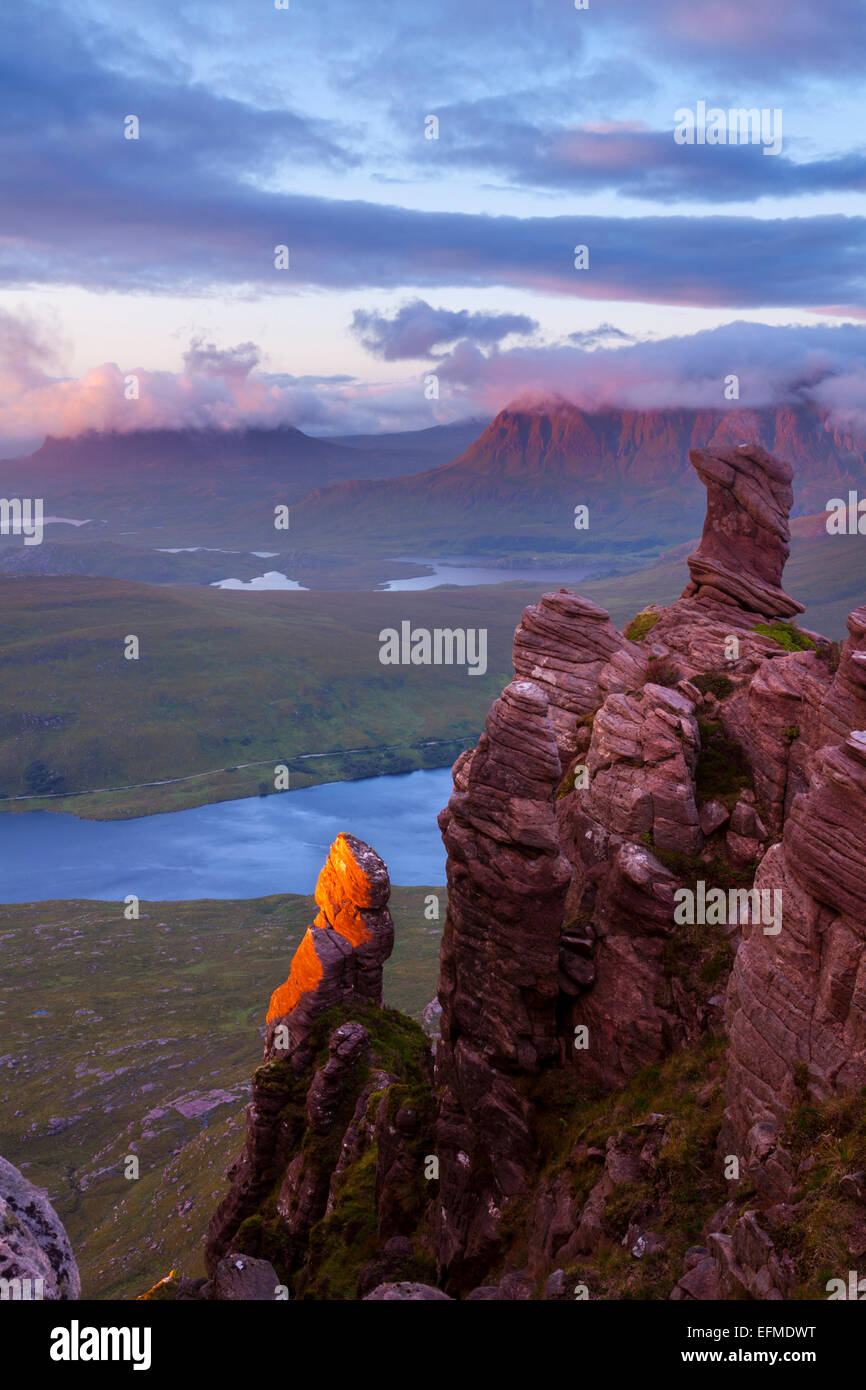 Bella arenaria Torridonian formazioni rocciose incandescente in rosso luce della sera con Suilven e Cul Mor in Assynt in backgroun Foto Stock