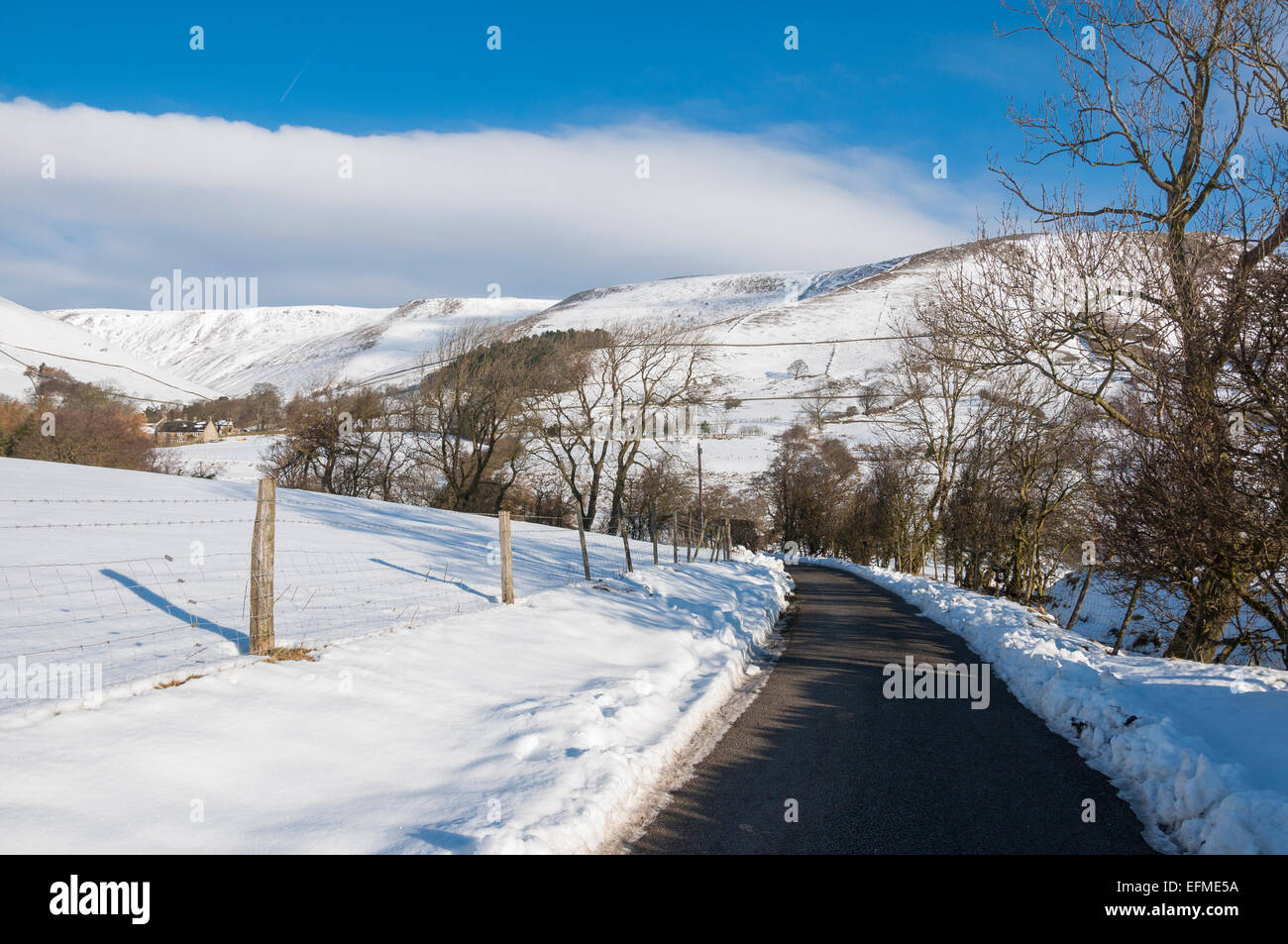 Strada per Upper Booth nella valle di Edale in una giornata di inverni soleggiati e innevati. Derbyshire, Inghilterra. Foto Stock