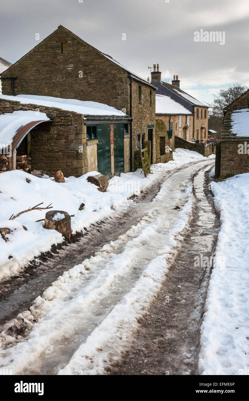 Il Peak District farm in inverno con coperta di neve Agriturismo via e gli edifici in pietra. Foto Stock