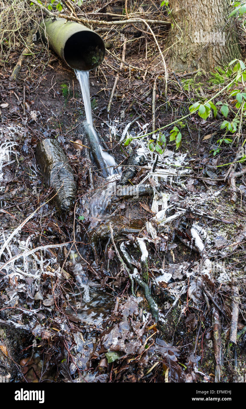 L'acqua da un acciaio tubo di drenaggio su un suolo ghiacciato. Foto Stock