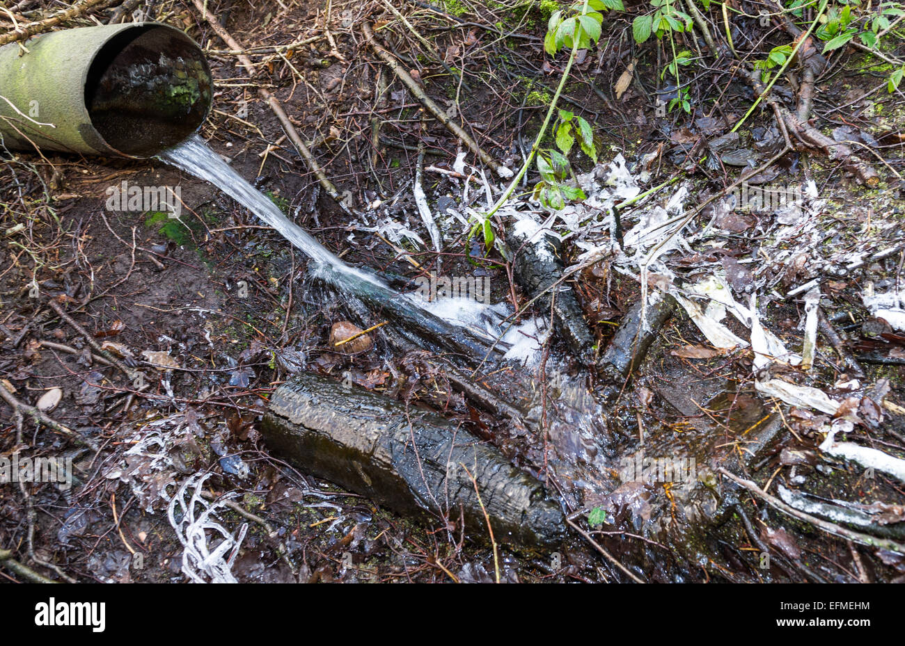 L'acqua da un acciaio tubo di drenaggio su un suolo ghiacciato. Foto Stock