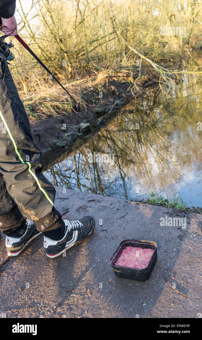 Ragazzo di pesca da un piccolo fiume utilizzando vermi come esca viva. Foto Stock
