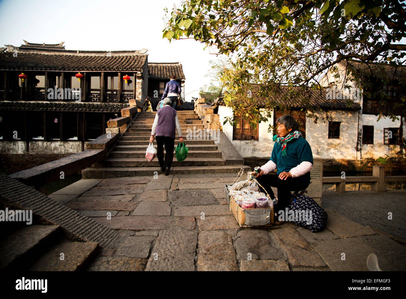 Donna vende locale tè naturale accanto al ponte di pietra al mattino. Foto Stock