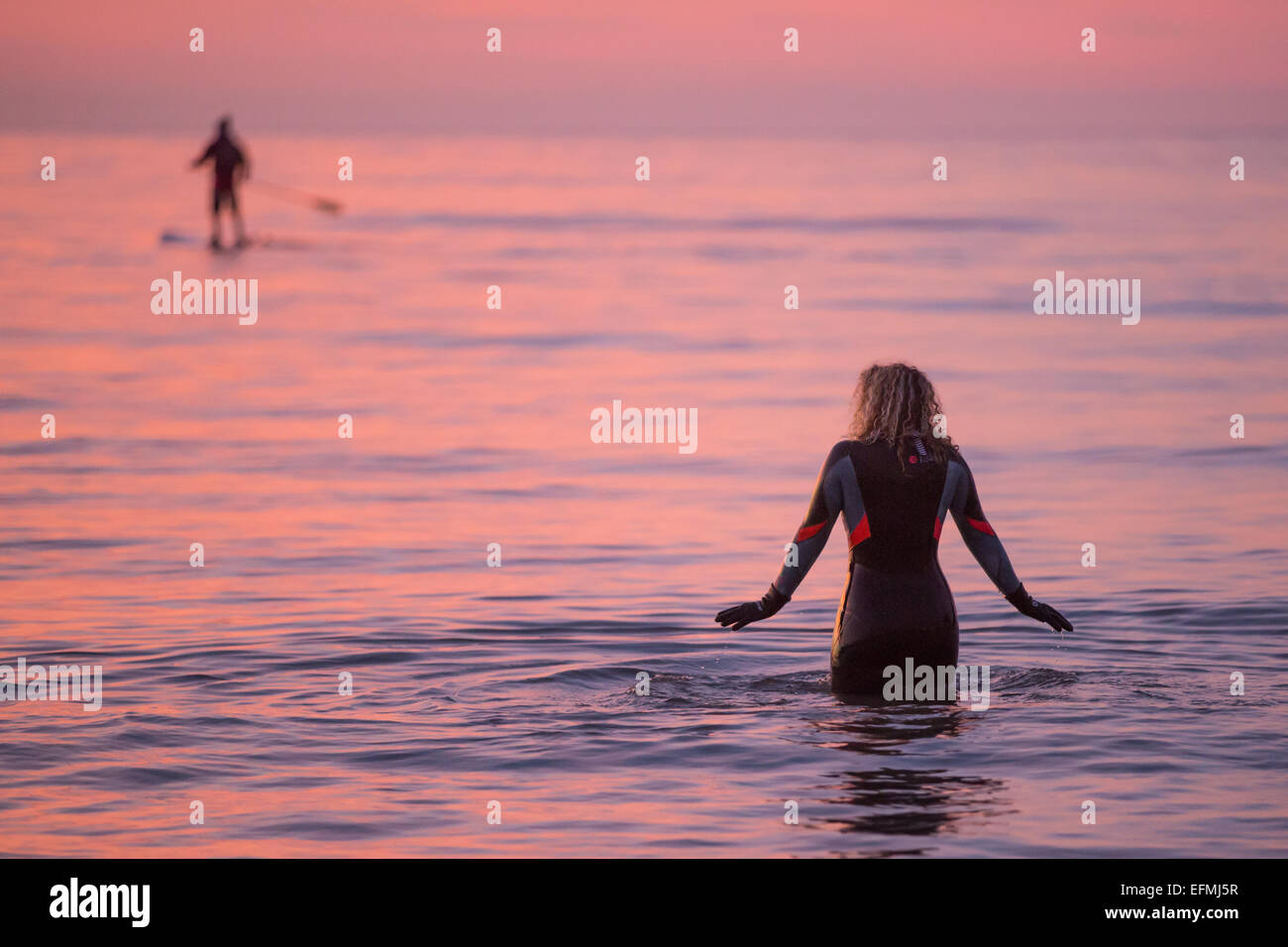 Aberystwyth, Wales, Regno Unito. 7 febbraio 2015. Meteo. Una donna wades in mare per una nuotata al tramonto Credito: Alan Hale/Alamy Live News Foto Stock