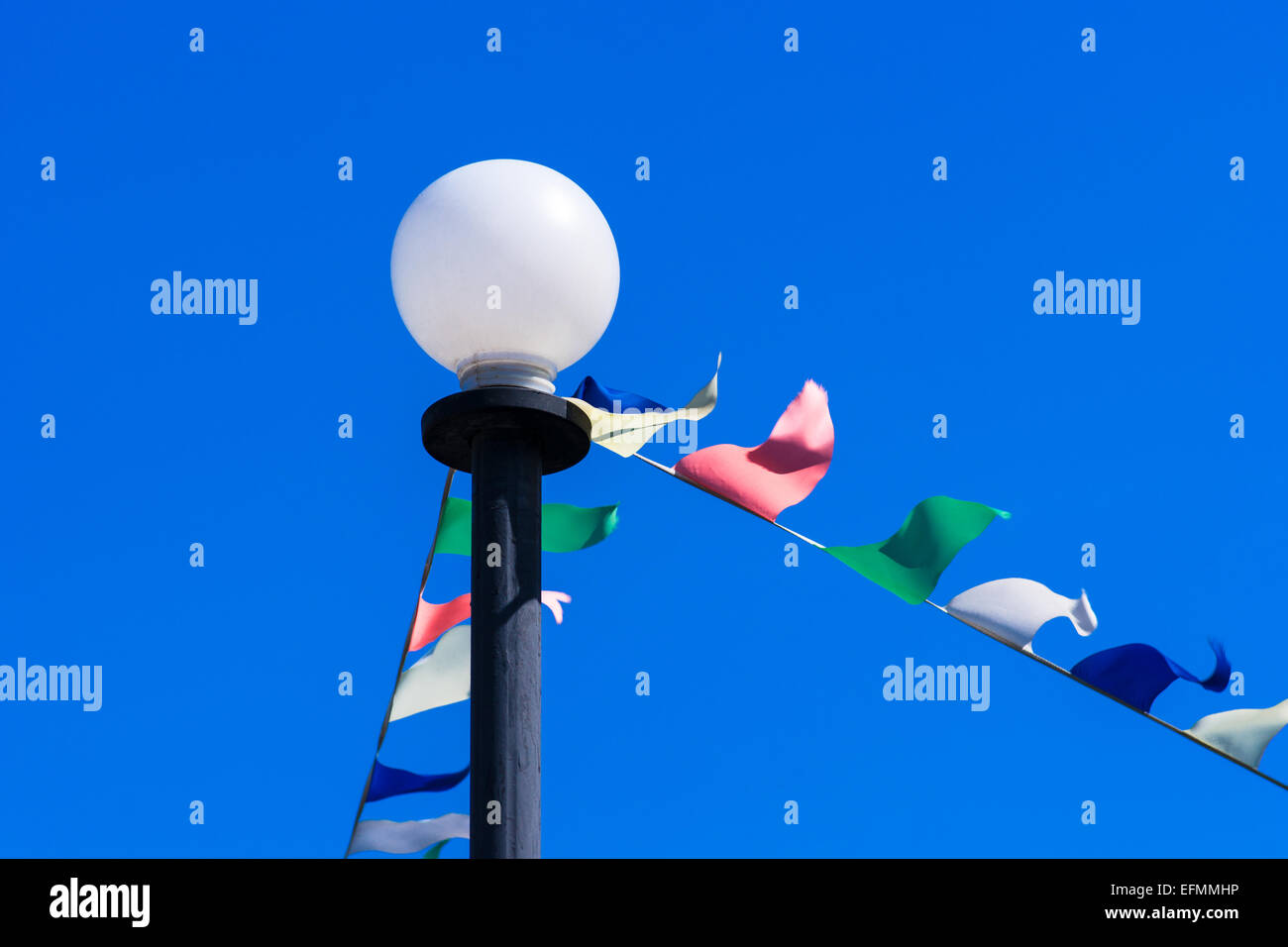 Strada bianca lampada e decorazione colorata bandiere contro lo sfondo del profondo cielo blu Foto Stock