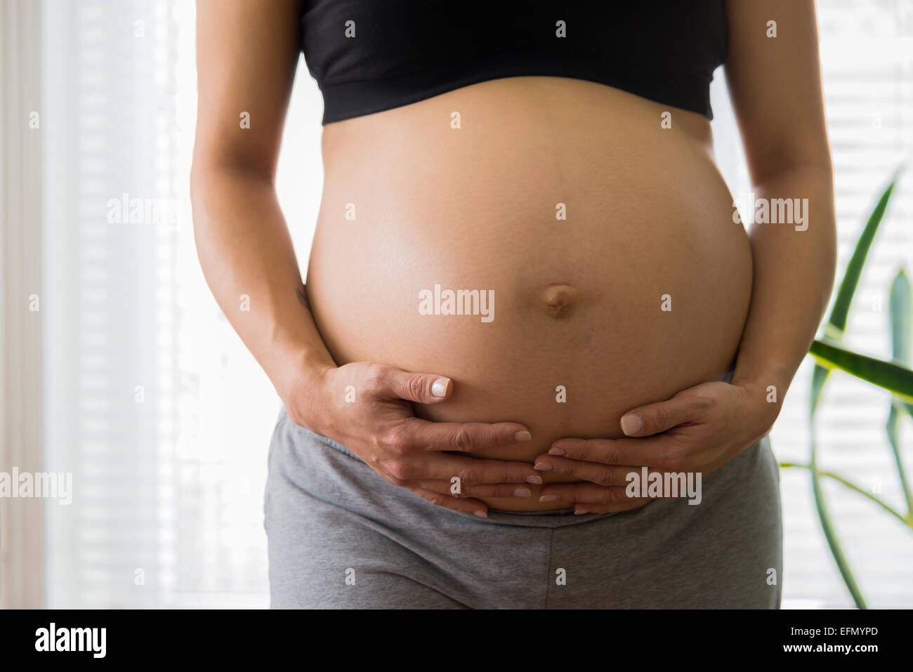 Baby bump, immagine di 8 mese donna incinta mentre tiene il suo bump Foto Stock