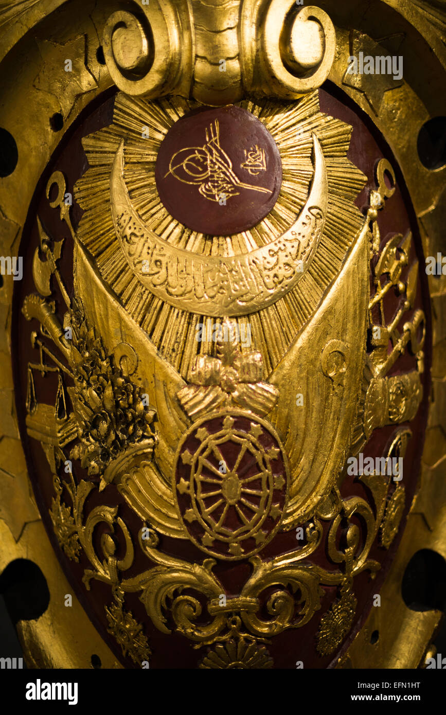 Museo Navale di Istanbul Sultan Abdulhamit II Tughra Stemma Ottomano Decorazione Navale Istanbul Turchia | ISTANBUL, Turchia — Una decorazione navale dorata e ornata raffigurante la tughra — il monogramma imperiale calligrafico — di Sultan Abdülhamid II (regno 1876–1909), combinata con motivi araldici ottomani tra cui bilance della giustizia, bandiere e ancore, è esposta al Museo Navale di Istanbul (İstanbul Deniz Müzesi) a Beşiktaş. Tali emblemi imperiali simboleggiavano il potere e l'autorità navale del tardo stato ottomano ed erano montati sulle navi da guerra per affermare l'identità sovrana. Il museo è stato fondato il 31 Foto Stock