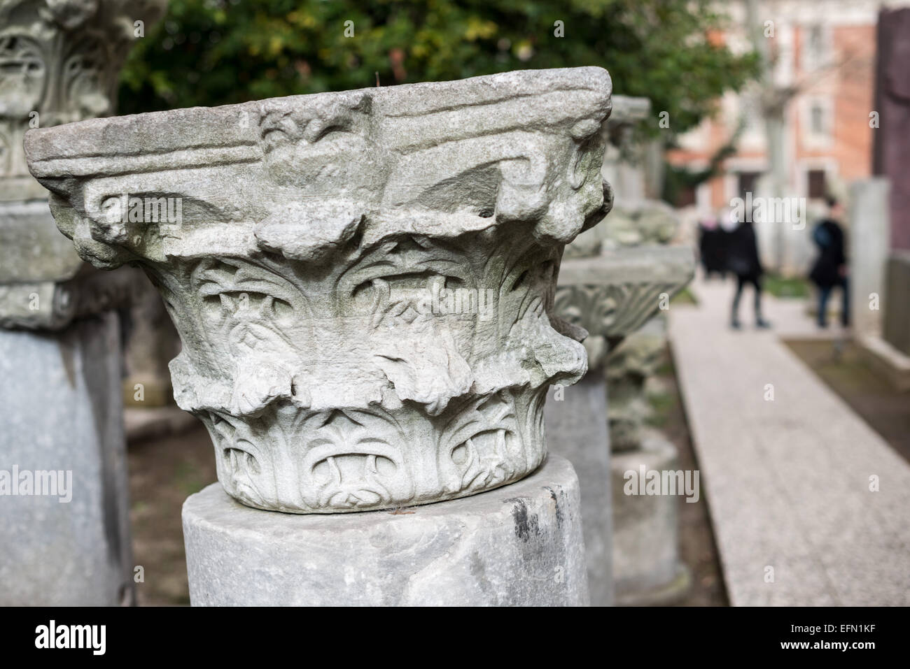 Capitello di colonna in marmo dei Musei Archeologici di Istanbul | ISTANBUL — Un capitello di colonna in marmo scolpito con foglie di acanto arricciate poggia lungo un sentiero del giardino nei Musei Archeologici di Istanbul, nel distretto di Gülhane. Il design stilizzato del fogliame è tipico dei frammenti architettonici recuperati dalle epoche romana e bizantina della città, raccolti qui mentre la collezione del museo superava circa un milione di oggetti sotto la direzione del fondatore Osman Hamdi Bey. Foto Stock