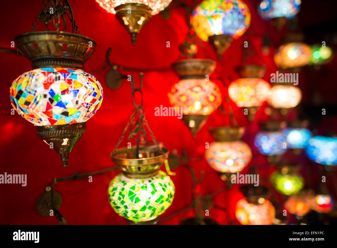 ISTANBUL, Turchia: Vivaci lampade in vetro a mosaico illuminano un negozio nello storico Grand Bazaar di Istanbul. La gamma colorata di lampade tradizionali turche crea un'abbagliante esposizione di artigianato artigianale. Queste lampade distintive, che combinano vetro colorato e metallo, rappresentano uno dei molti mestieri tradizionali disponibili in questo mercato secolare. Foto Stock