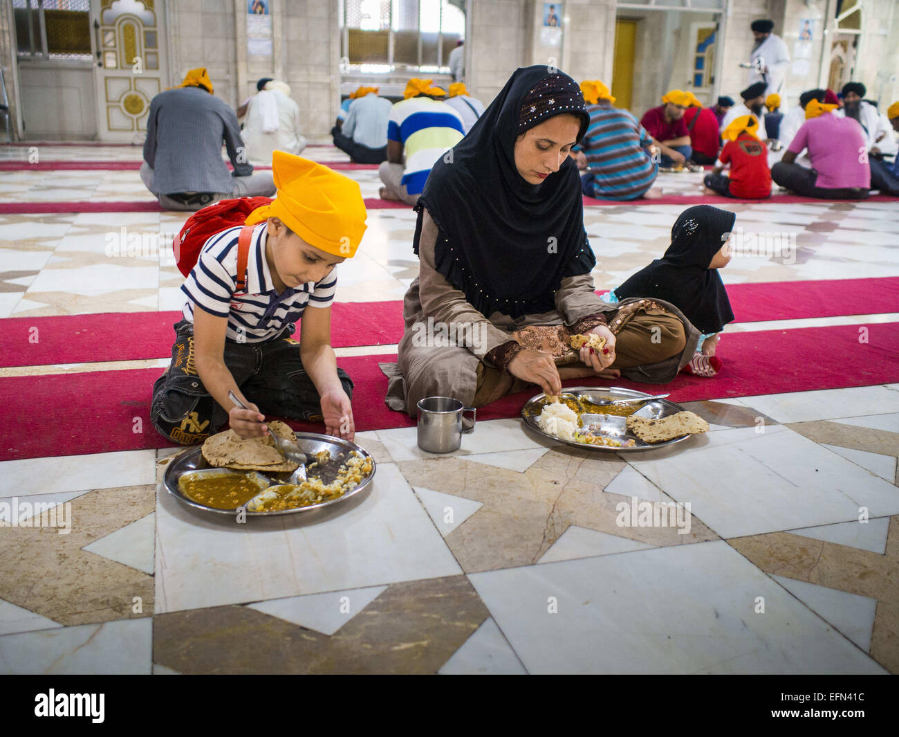 Bangkok, Bangkok, Thailandia. 8 febbraio, 2015. Una donna musulmana e i suoi figli a terminare la prima colazione durante il pasto comunitario presso il tempio sikh in Bangkok. La Tailandia ha una piccola ma influente comunità sikh. I sikh ha iniziato a venire in Thailandia, allora Siam, nel 1890s. Ora ci sono diverse migliaia di Thai-Indian famiglie Sikh. Il tempio sikh in Bangkok, Gurdwara Siri Guru Singh Sabha, è stato istituito nel 1913. L'edificio attuale, adiacente all'originale Gurdwara (''Gateway al Guru''), è stato costruito nel 1979. La comunità sikh serve un quotidiano gratuito pasto vegetariano al Gurdwara che è trattati Foto Stock