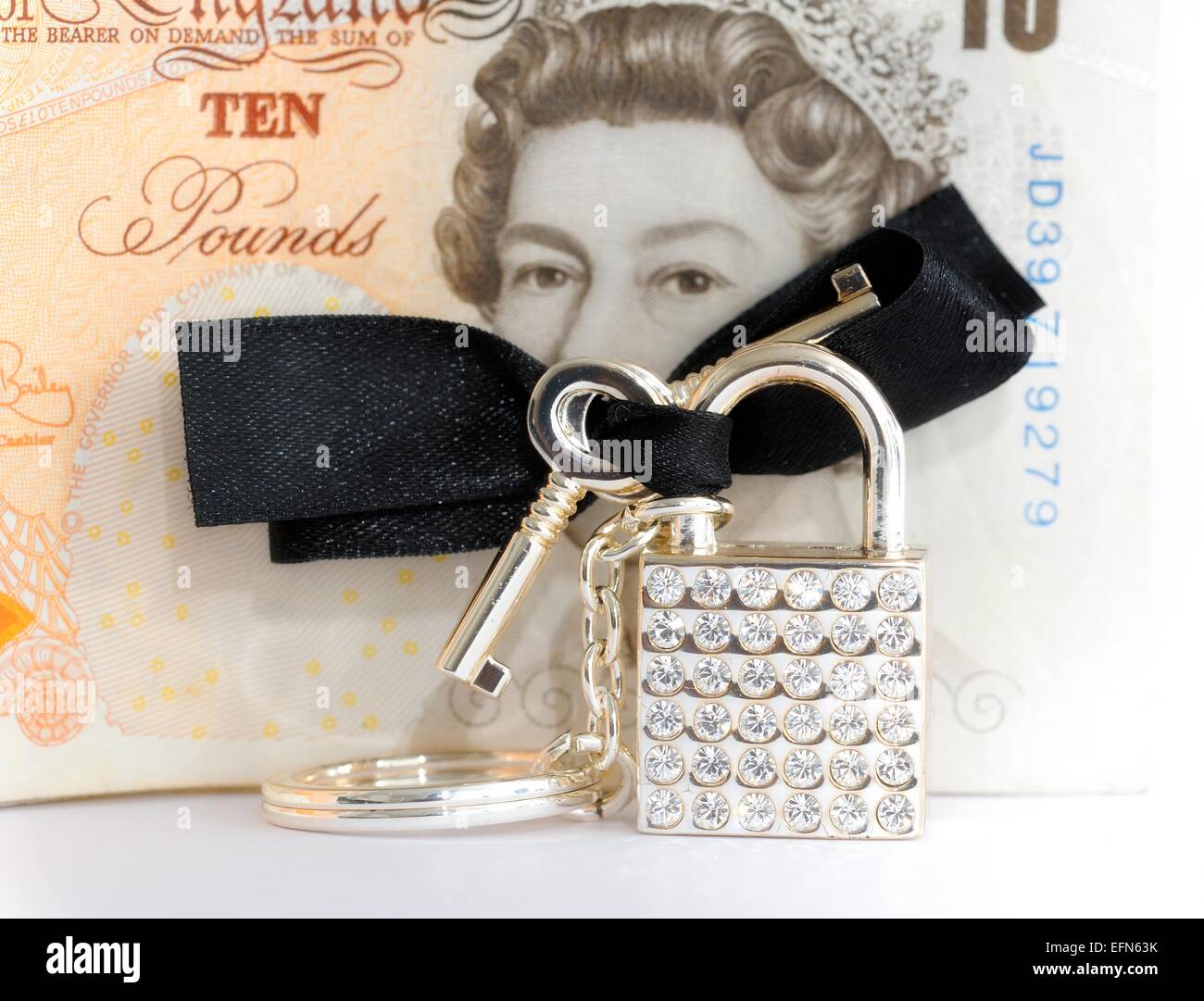 Un bling chiave lucchetto ad anello nero con un inchino davanti a un britannico dieci pound nota Foto Stock