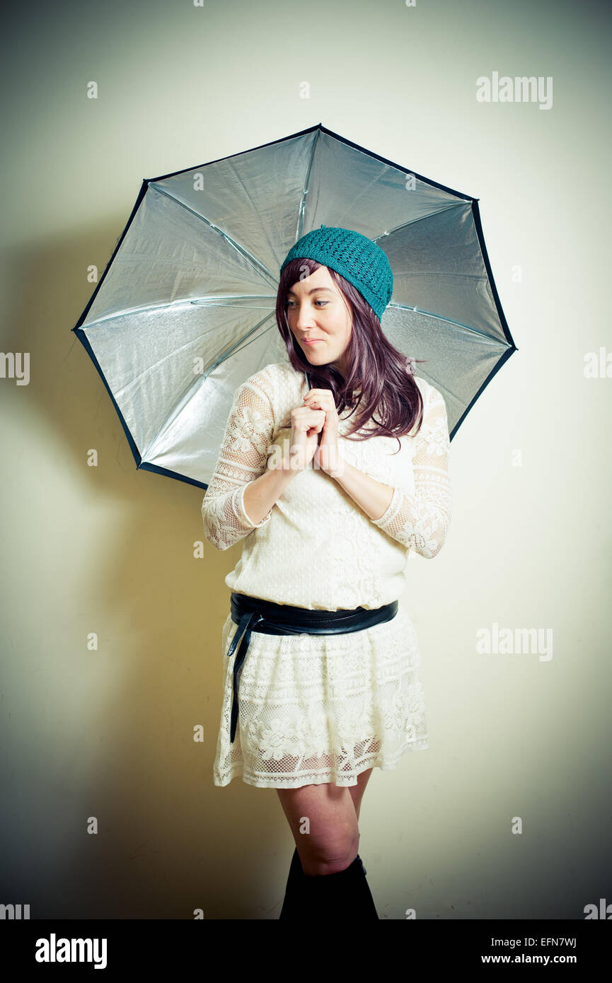 Giovane donna in 70s stile hippie in posa guardando in giù con ombrello vintage effetto colore Foto Stock