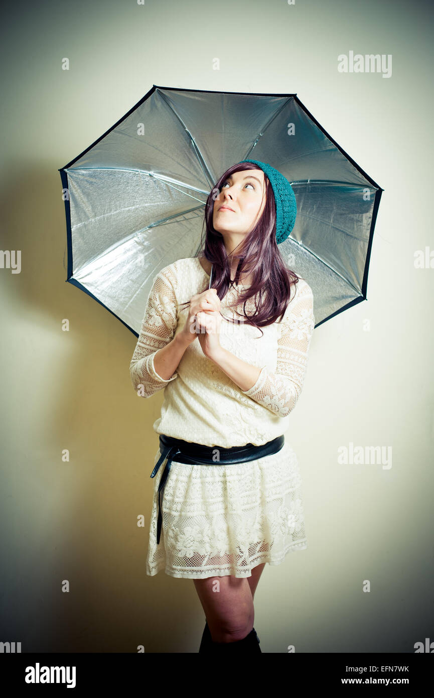 Giovane donna in 70s stile hippie in posa cercando con ombrello vintage effetto colore Foto Stock