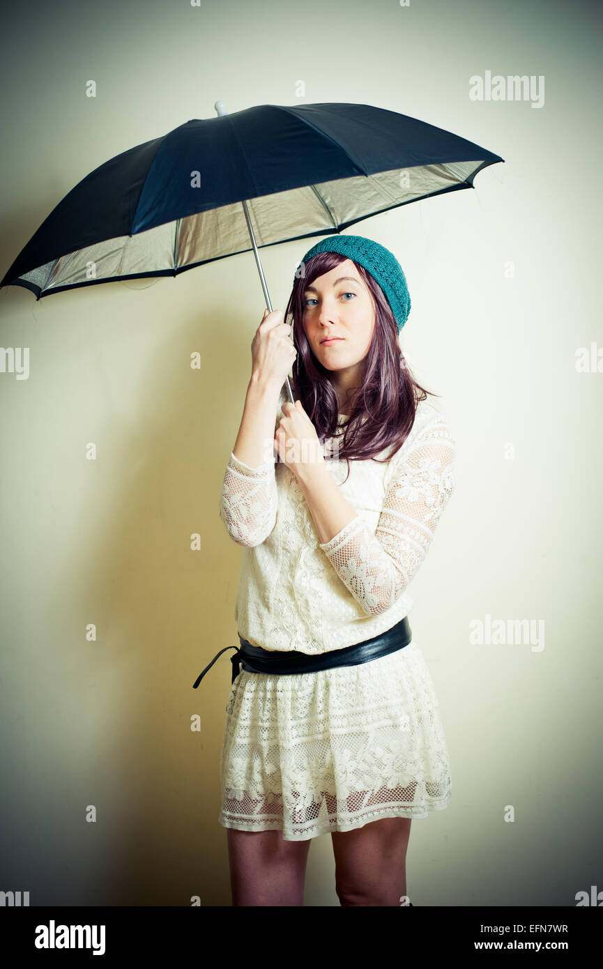 Giovane donna in 70s stile hippie in posa con ombrello vintage effetto colore Foto Stock