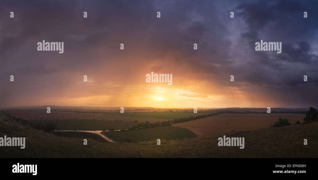 Tramonto colorato e drammatico cielo sopra il paesaggio illuminato Foto Stock