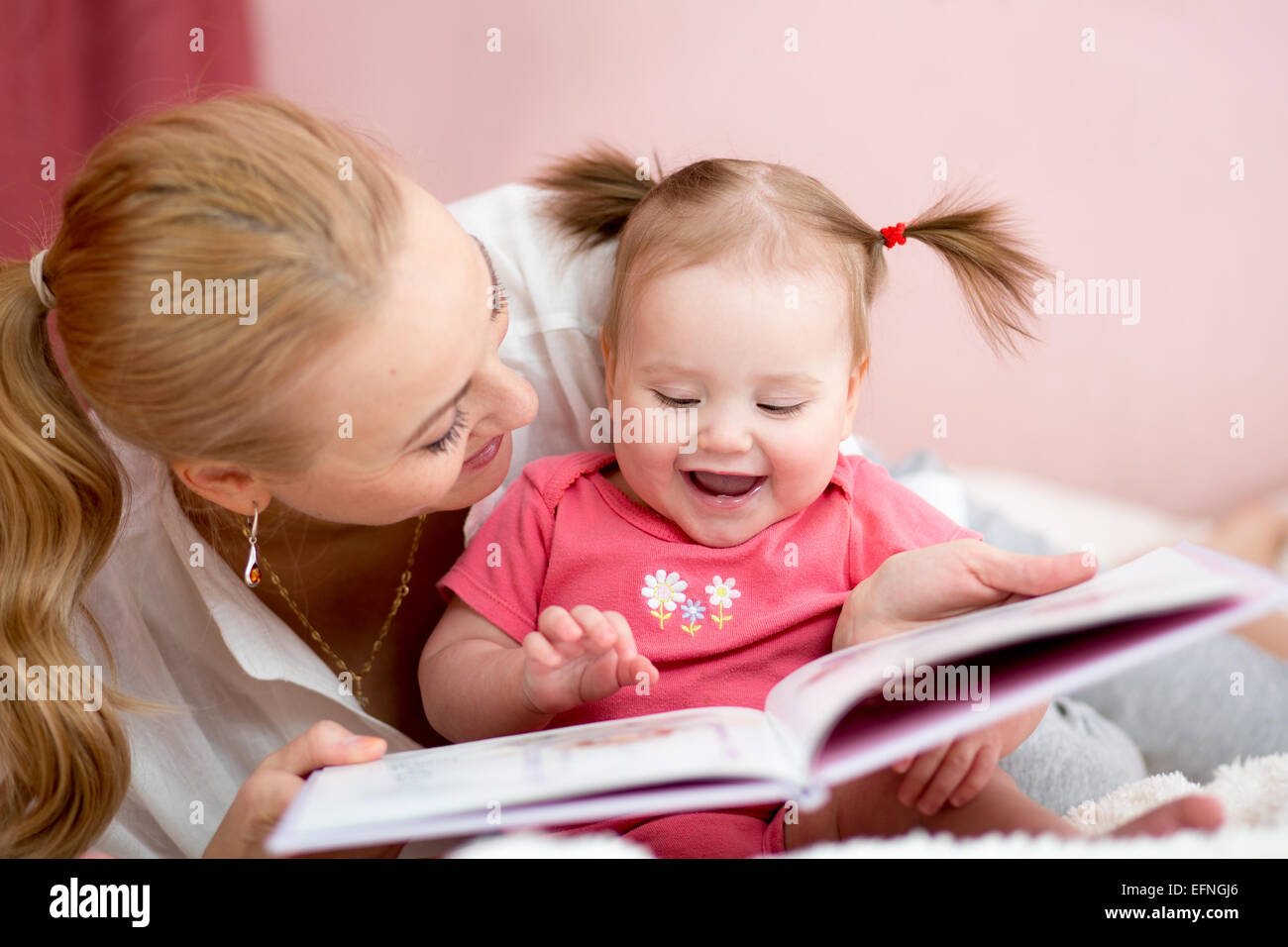 Madre felice di leggere un libro per bambini ragazza Foto Stock