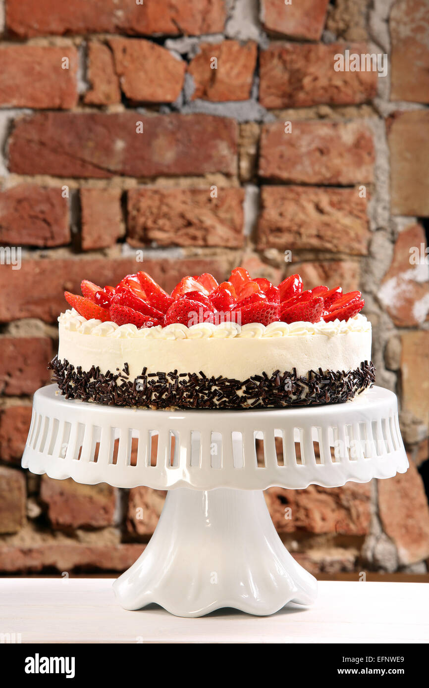 Crema di fragole la torta su un muro di mattoni sfondo Foto Stock