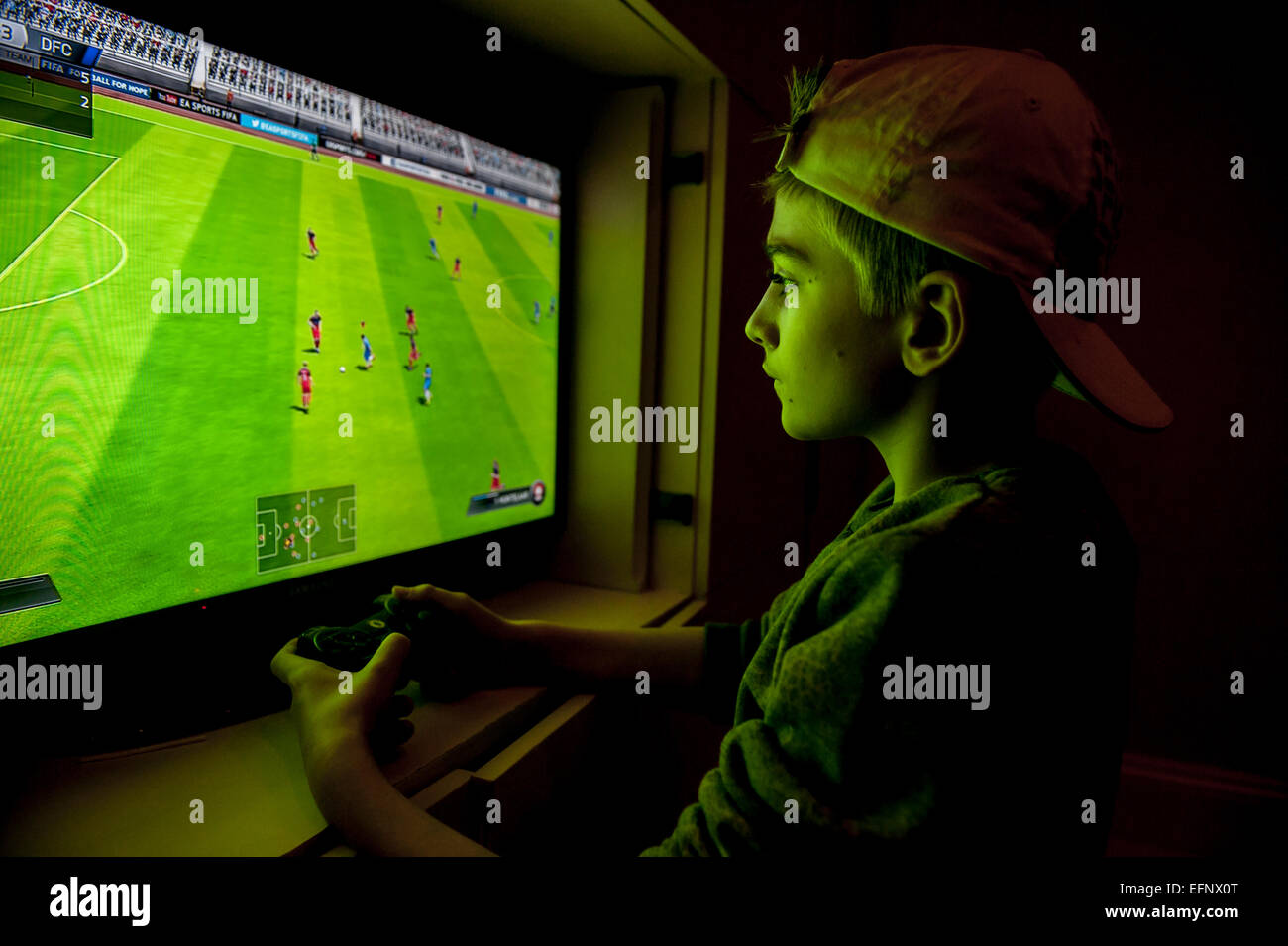 Un ragazzo con un cappello da baseball al contrario gioca una partita di  calcio con la sua console per videogiochi Foto stock - Alamy