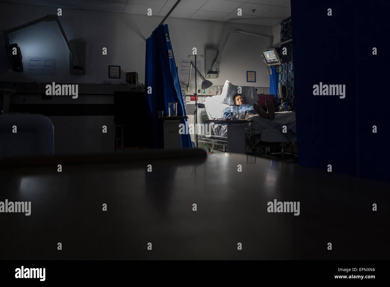 Un vecchio uomo nel letto di un ospedale con un sacco di attrezzature di notte Foto Stock