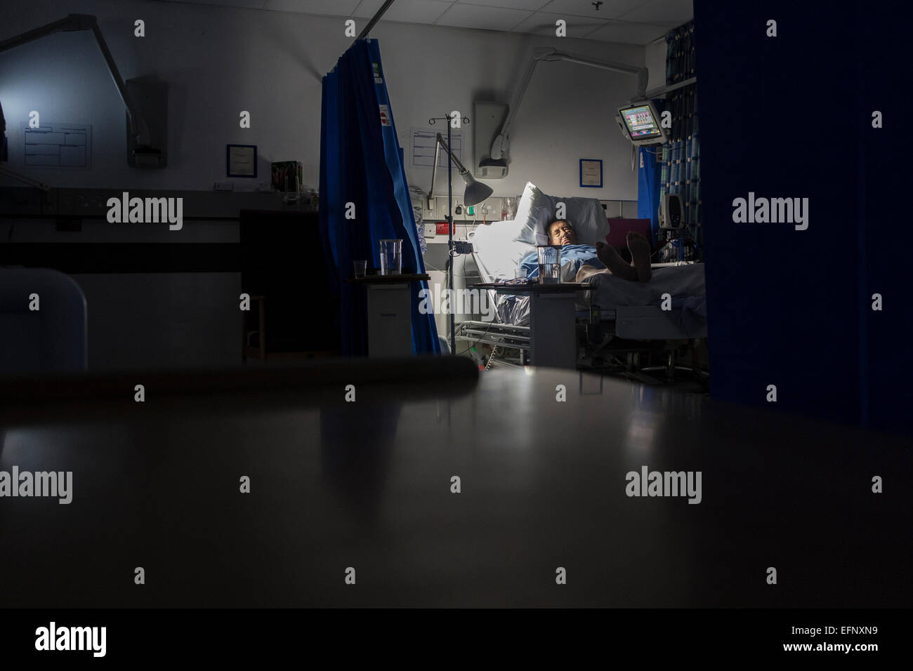 Un vecchio uomo nel letto di un ospedale con un sacco di attrezzature di notte Foto Stock