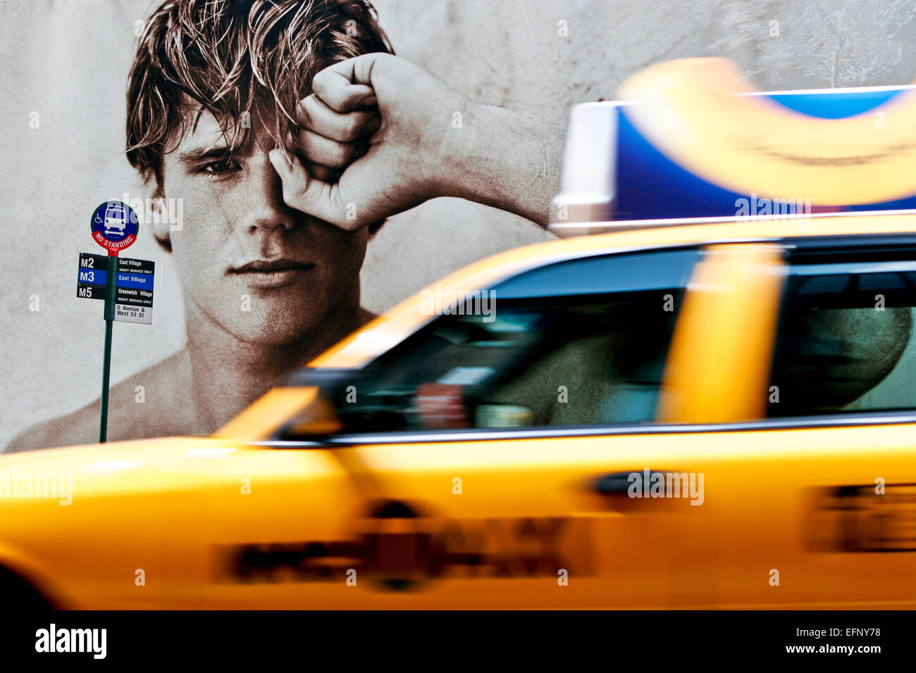 Bel giovane maschio modello sulla moda cartelloni pubblicitari presso la fermata degli autobus, taxi giallo taxi motion blur passando. Quinta Avenue a Manhattan, New York City, NY Foto Stock