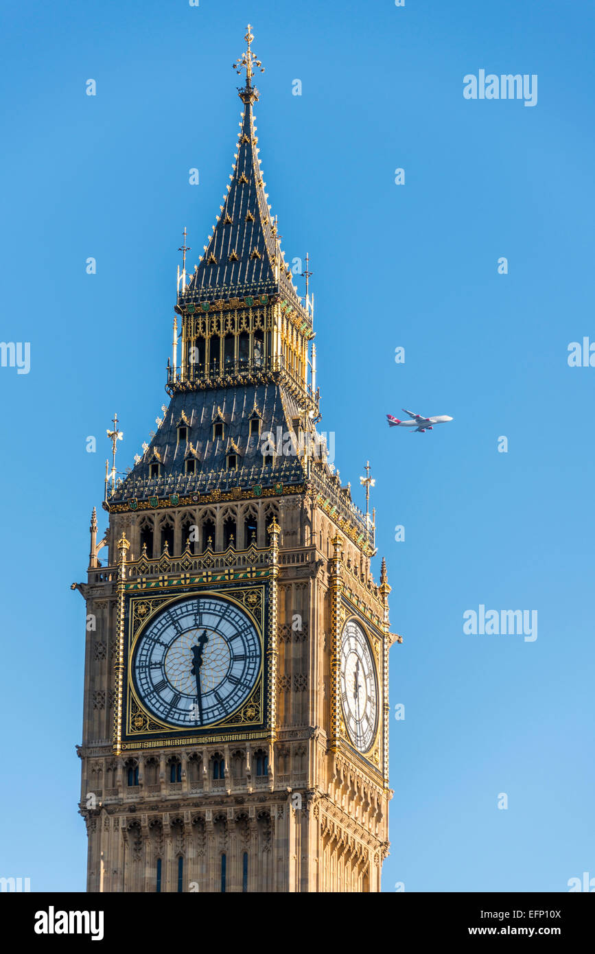 Un aereo pases dietro il Queen Elizabeth Tower, meglio conosciuto come Big Ben, un iconico punto di riferimento di Londra Foto Stock