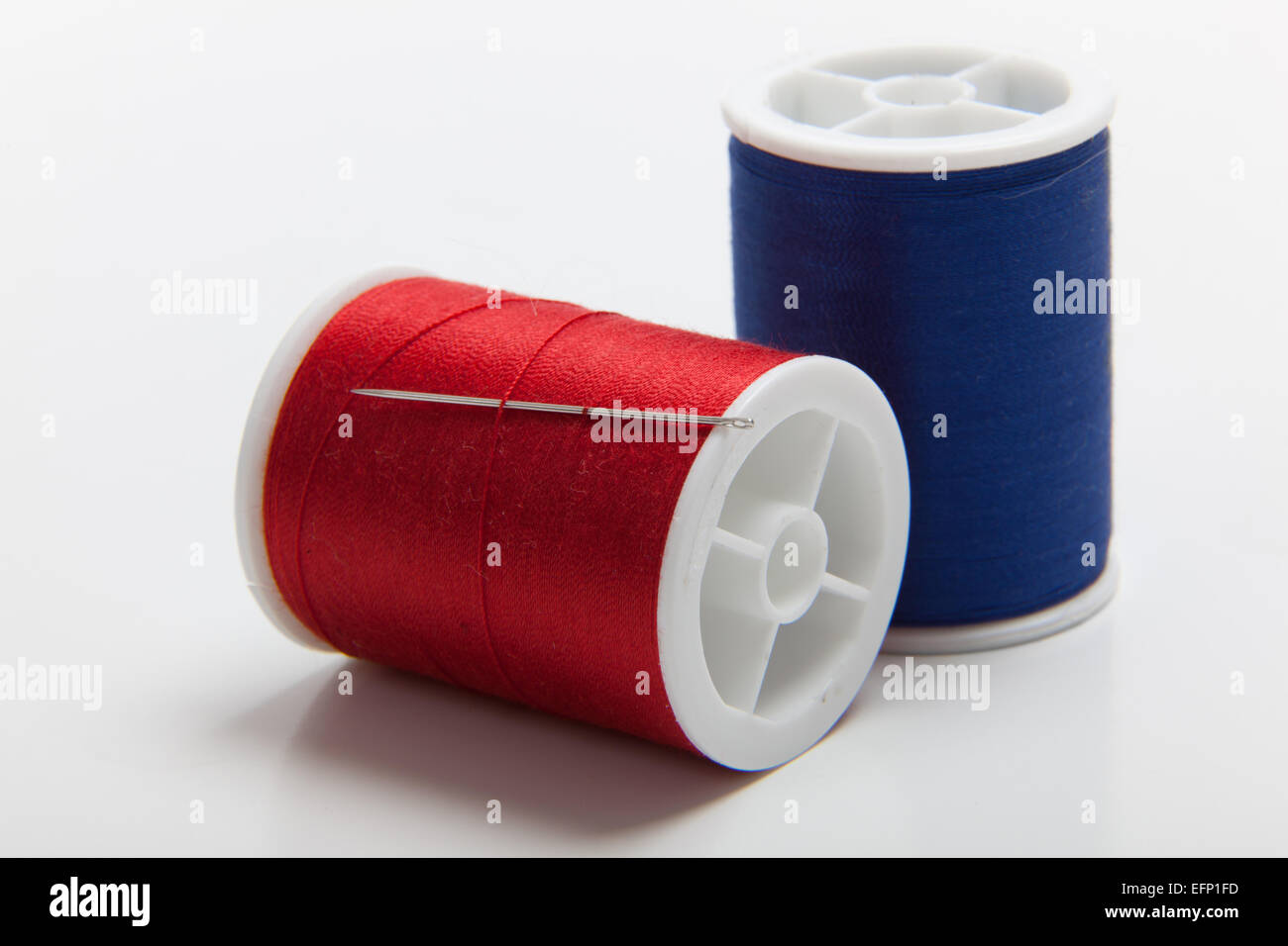 Bobine di rosso e blu per cucire con un ago di cucitura Foto Stock