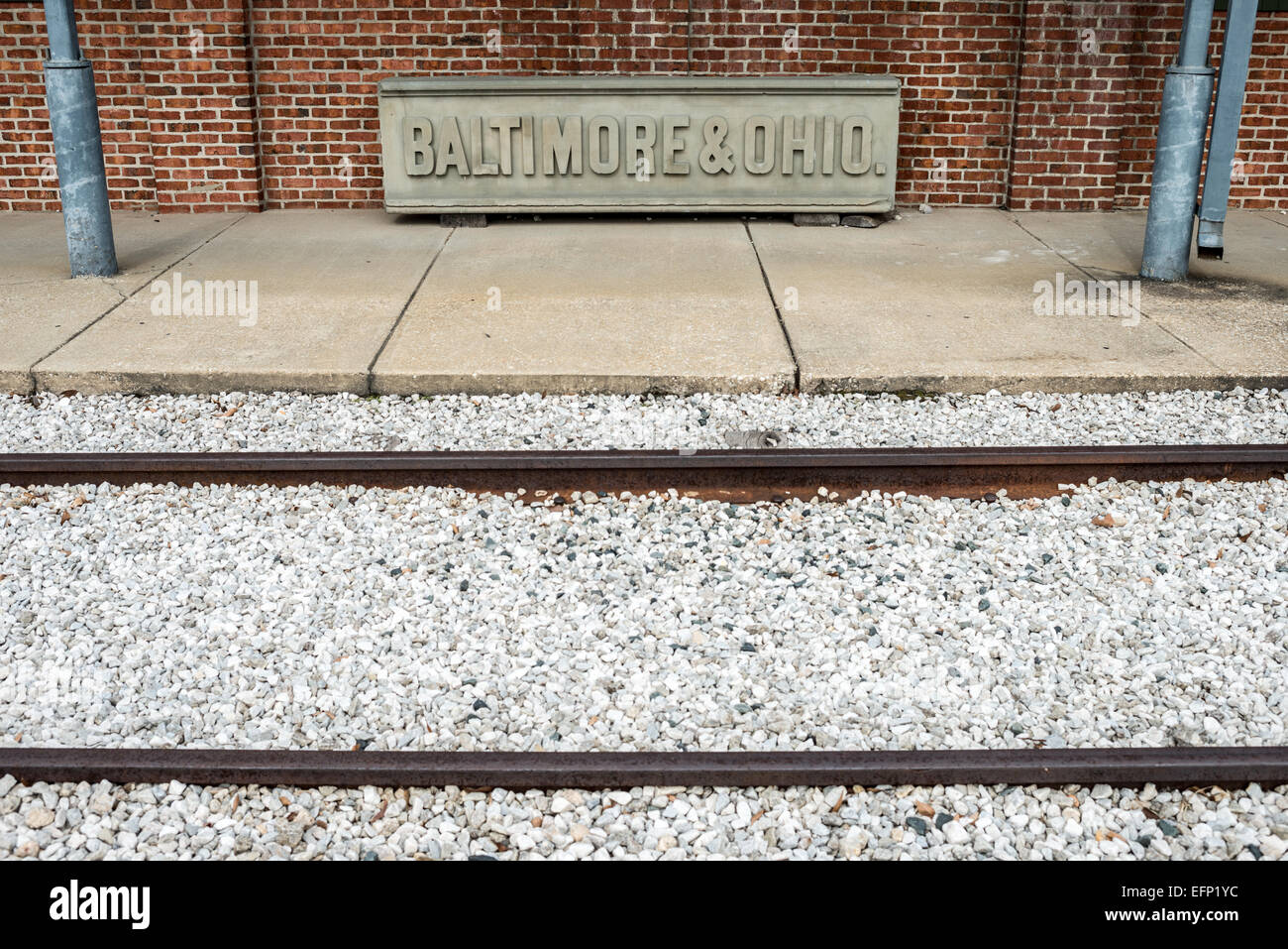 B&o Railroad Museum Sign Train Tracks Baltimore Maryland // BALTIMORE, Maryland — i binari dei treni corrono di fronte a un vecchio cartello ferroviario in pietra della B&O. Il B&o Railroad Museum di Mount Clare a Baltimora, Maryland, ha la più grande collezione di locomotive del XIX secolo negli Stati Uniti. Foto Stock
