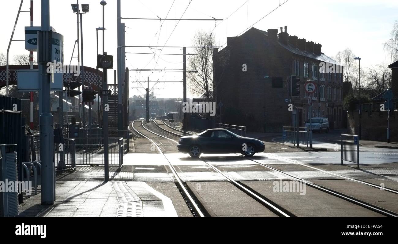 Il passaggio di un auto rispetto a David lane tram e incrocio ferroviario Basford, Nottingham. In Inghilterra. Regno Unito. Foto Stock