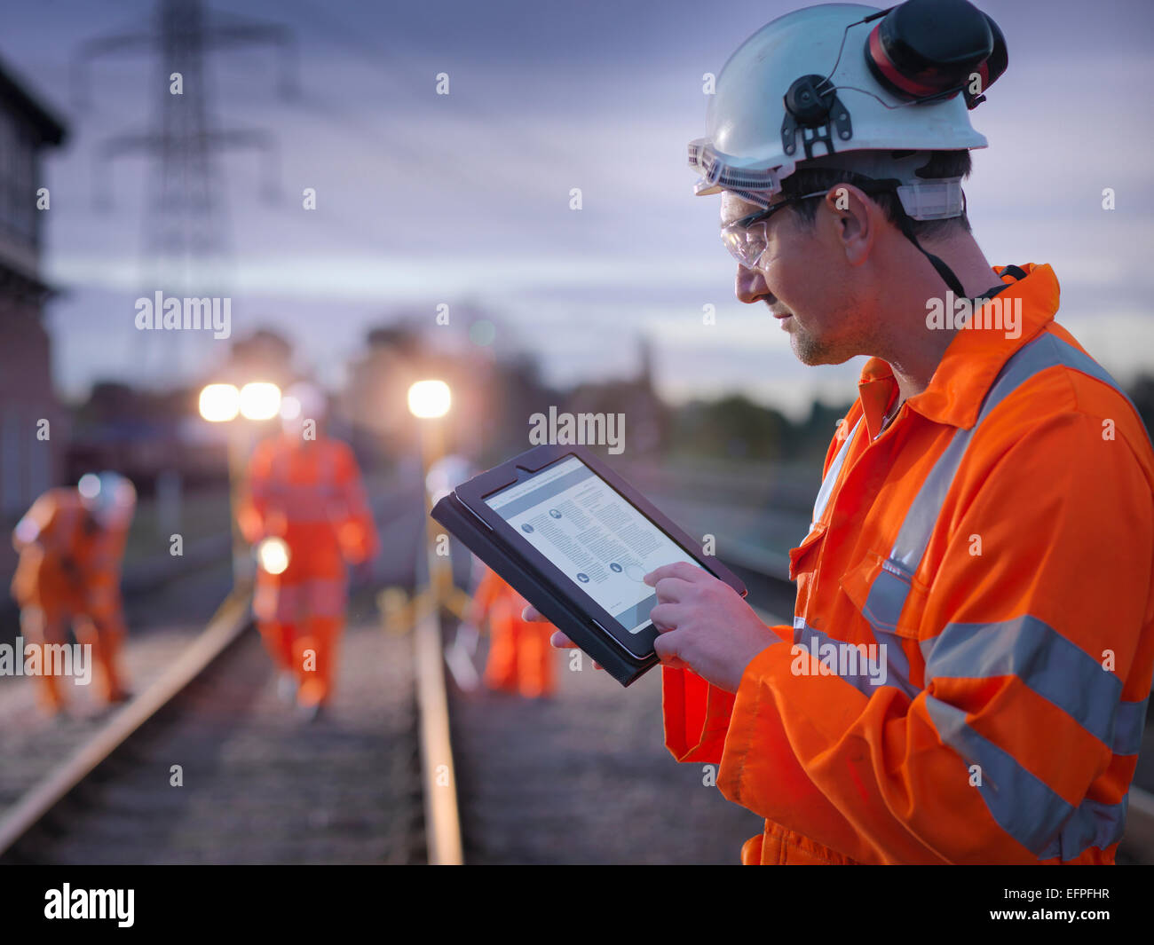 Manutenzione ferroviaria lavoratore utilizzando tavoletta digitale di notte Foto Stock
