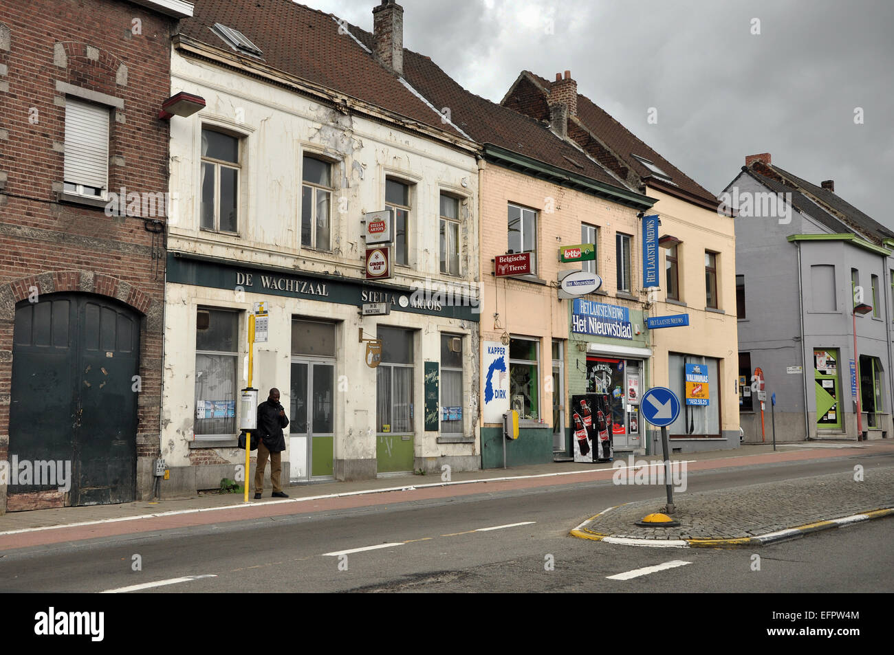 ASSE, Belgio - giugno 2011 l uomo ad una fermata del bus in un vuoto di strada con edifici abbandonati Foto Stock