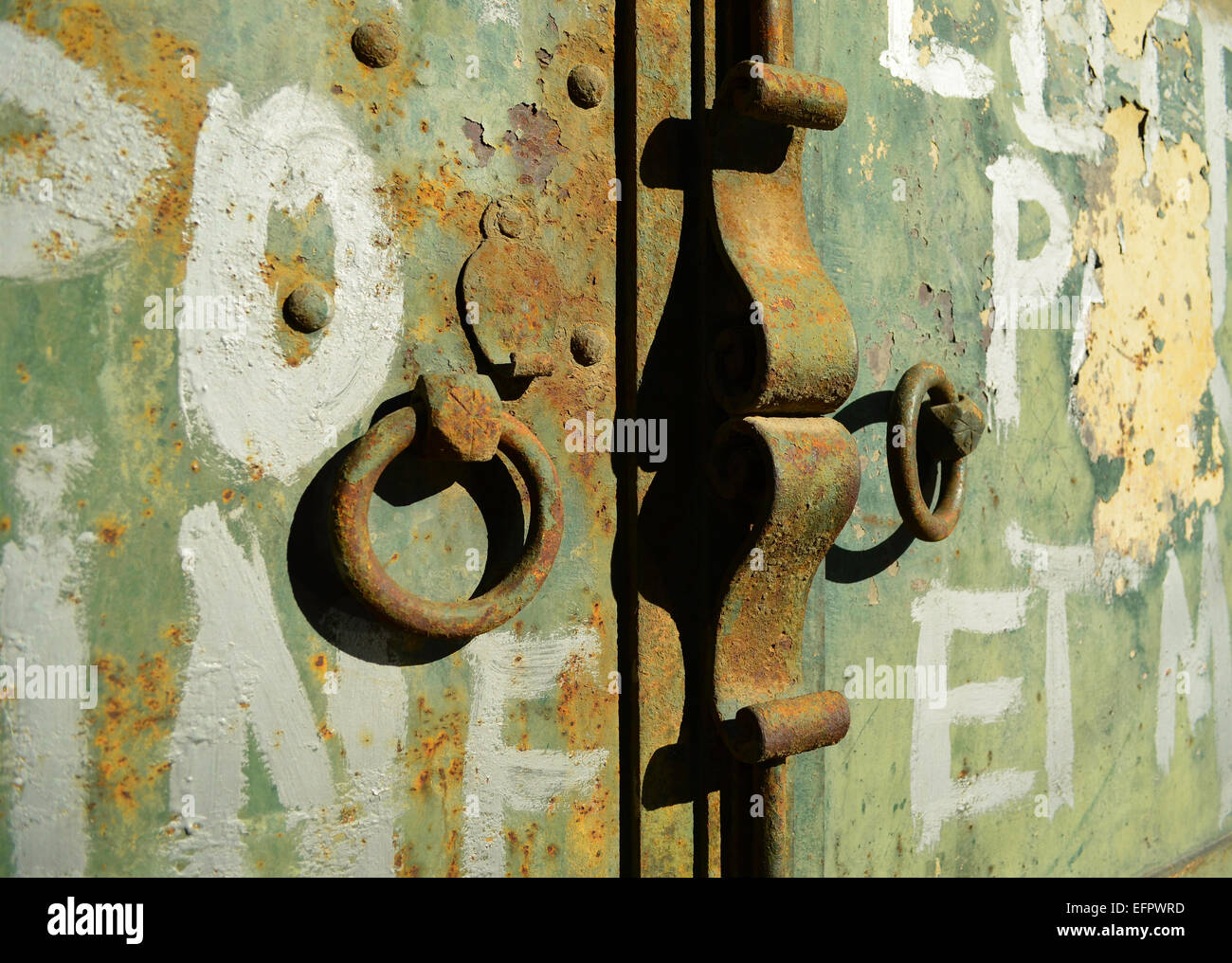Close up shoot di rusty vecchia porta con gli anelli di bloccaggio e la manopola. Le lettere in bianco è stato scritto sulla luce della vernice verde. Foto Stock