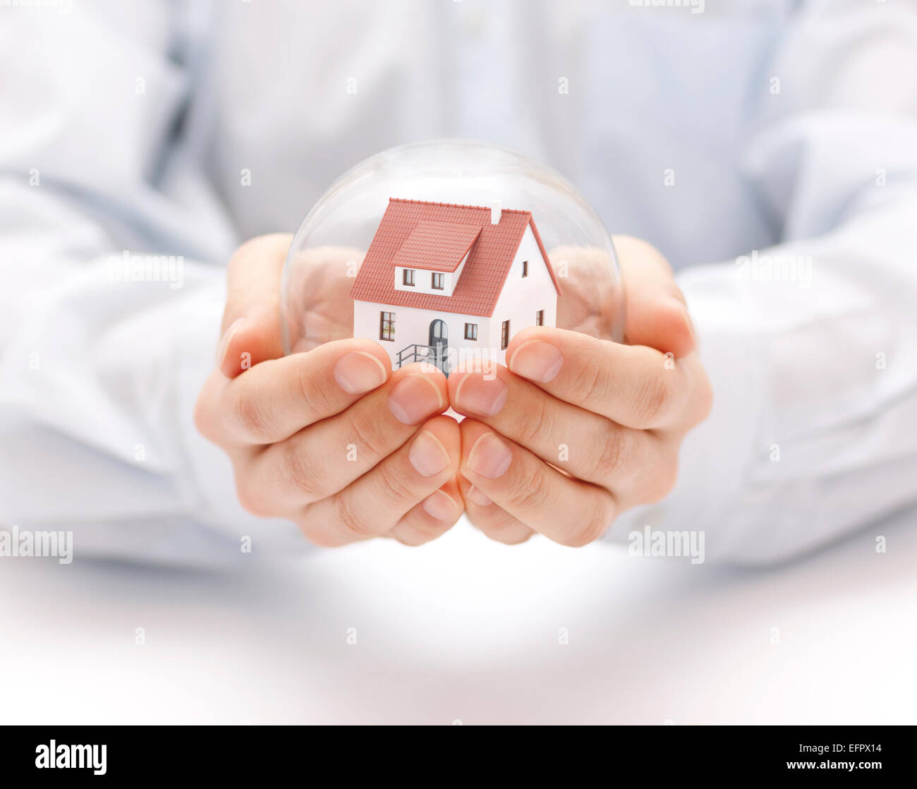 Sfera di cristallo con casa in mani Foto Stock