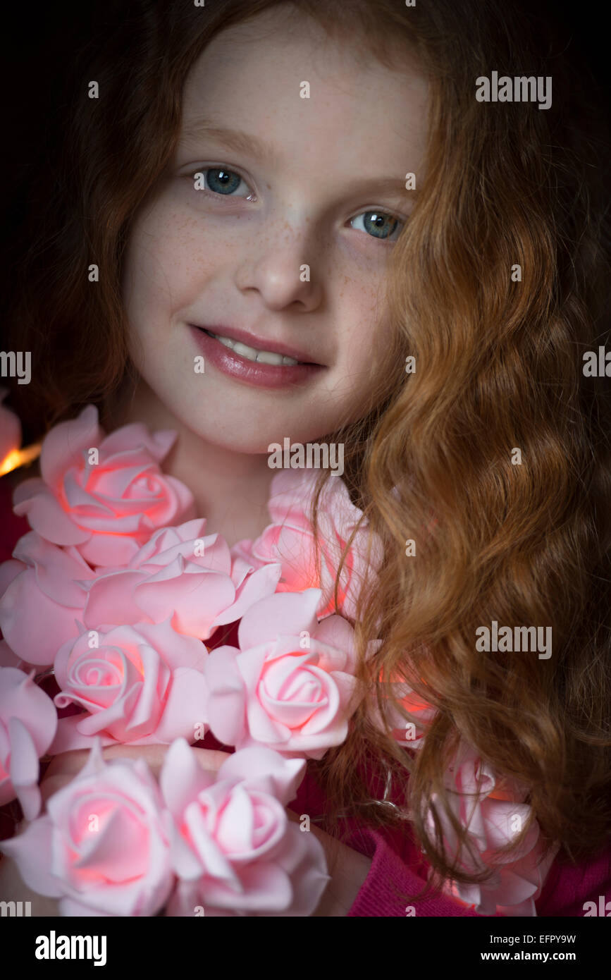 Ritratto di una bambina con una ghirlanda di rose intorno al suo collo. Foto Stock