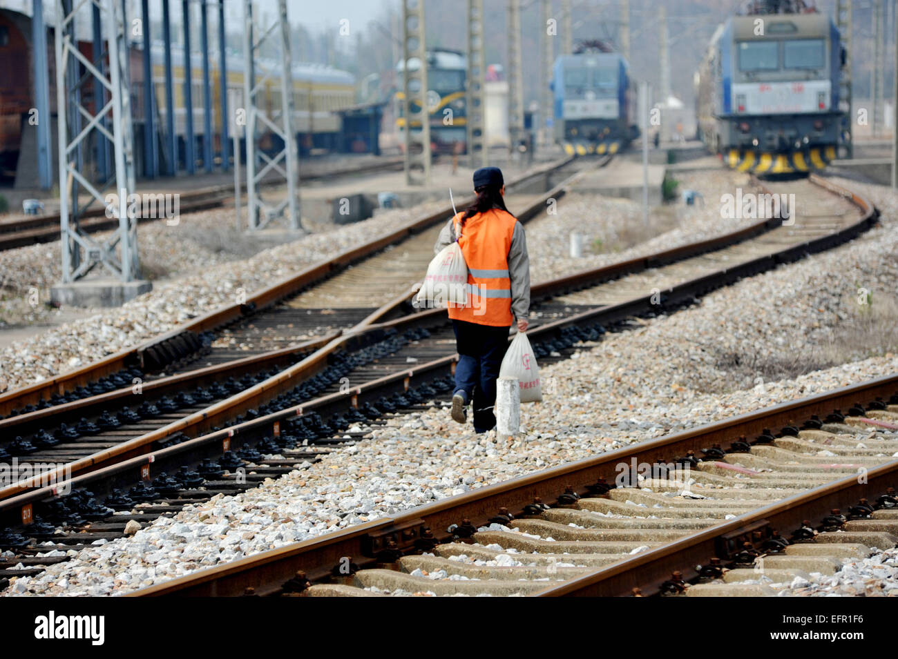 Shangrao, la Cina della provincia di Jiangxi. Il 9 febbraio, 2015. Greaser Ye Suihua porta due sacchetti di sabbia lungo una linea ferroviaria in corrispondenza di una stazione di Shangrao, Cina orientale della provincia di Jiangxi, Febbraio 9, 2015. Il 40-giorno travel frenzy noto come 'Chunyun', il periodo frenetico circostante il Festival di Primavera, che cade quest anno il 19 febbraio, ha avuto inizio il 4 febbraio e durerà fino al mese di marzo 16. © Zhuo Zhongwei/Xinhua/Alamy Live News Foto Stock