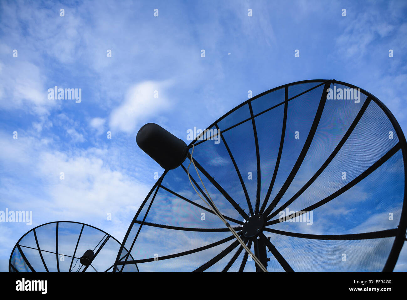 Nero a doppia parabola satellitare contro blu cielo nuvoloso la mattina presto Foto Stock