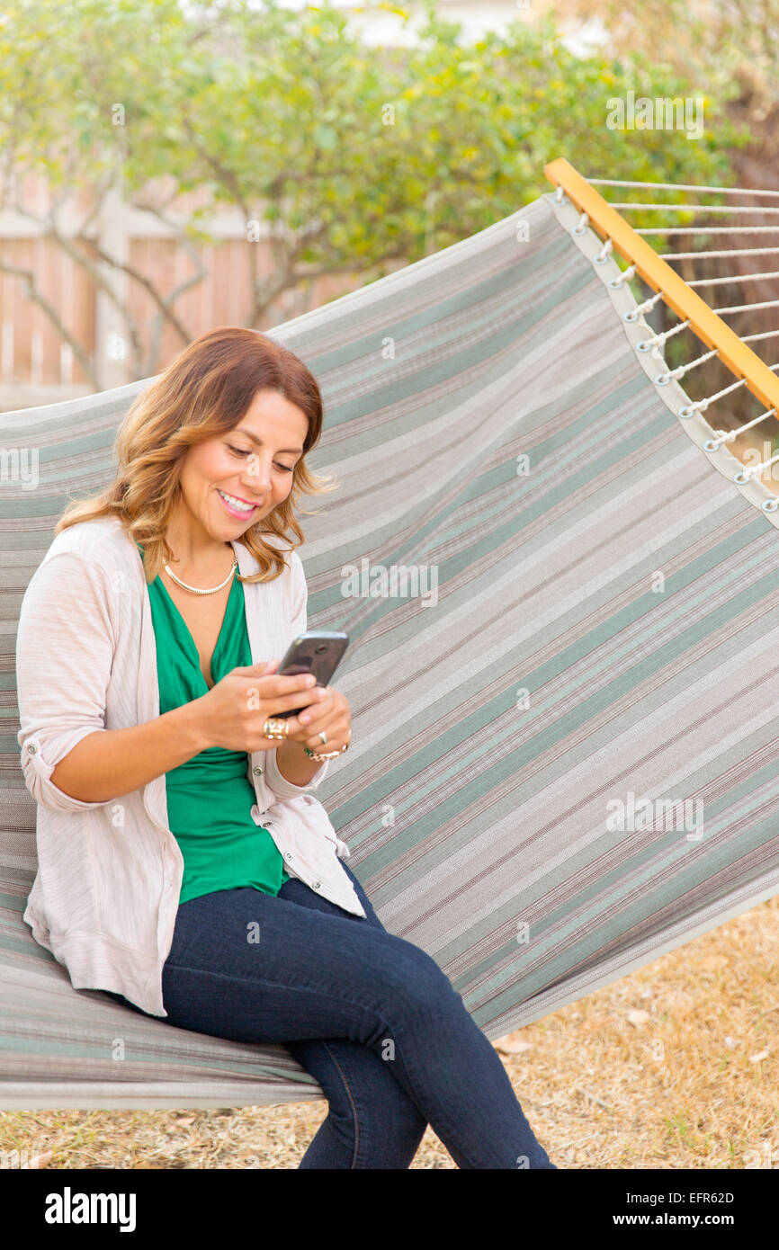 Donna che utilizza smartphone su amaca Foto Stock