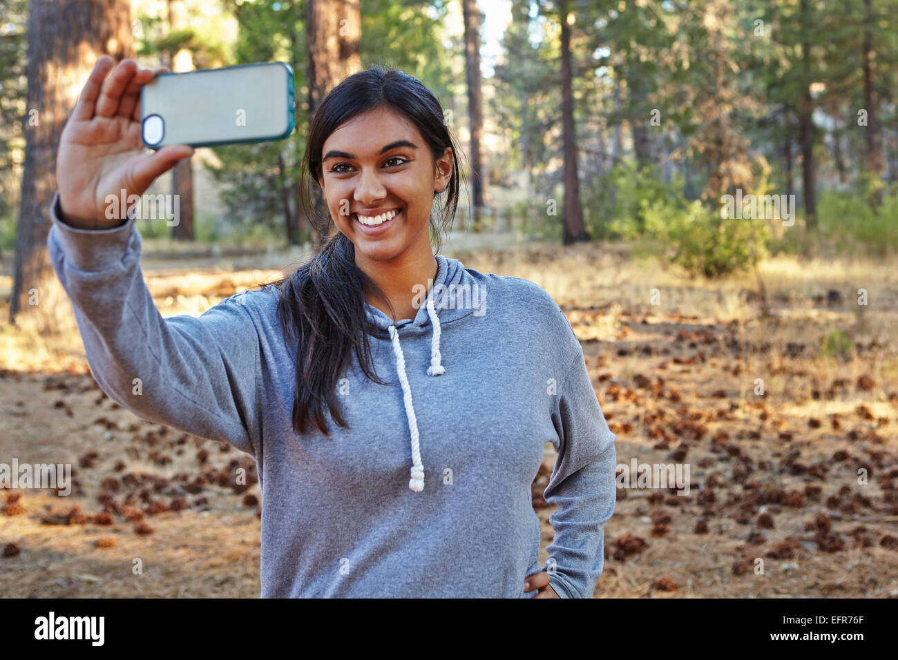 Giovane donna nella foresta prendendo selfie smartphone, Los Angeles, California, Stati Uniti d'America Foto Stock